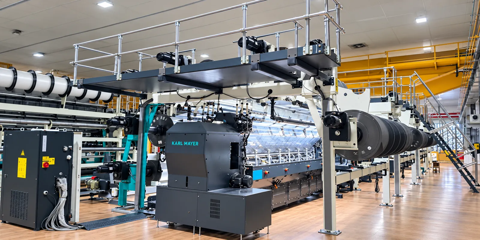 Karl Mayer warp knitting machine with warp beams and walkway in a production hall